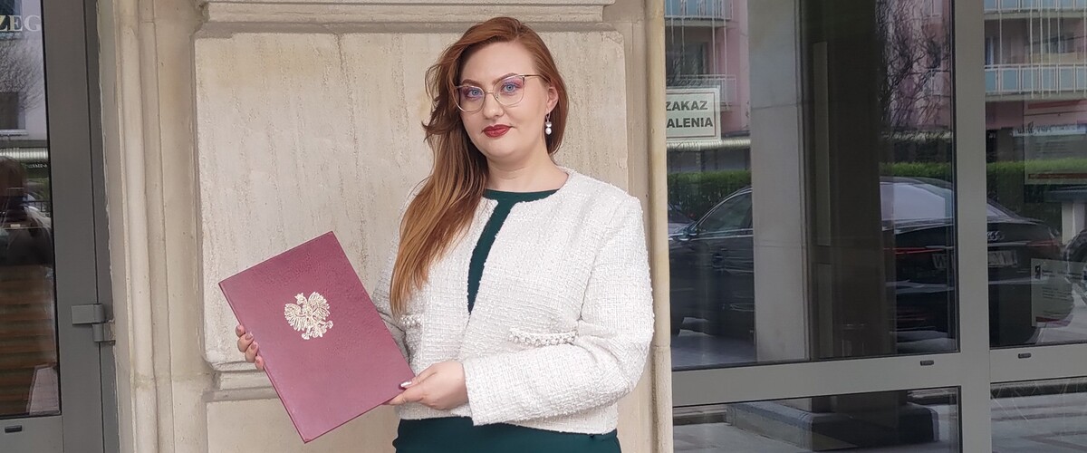 Magister Katarzyna Kowalik przy budynku Ministerstwa Nauki i Szkolnictwa Wyższego z listem gratulacyjnym