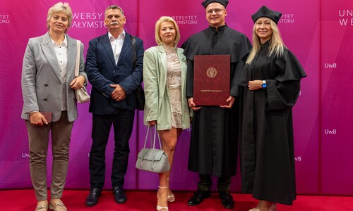 zdjęcie doktoranta na ściance UwB z rodziną